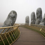 Photo of the "Golden Bridge" in Da Nang, Vietnam: A yellow-hued bridge is supported by two gigantic hands